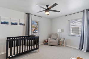 Bedroom featuring ceiling fan, light carpet flooring, 2 large windows