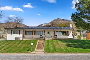 View of front facade featuring a front yard, a mountain view, metal roof, a chimney
