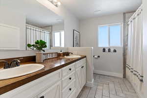 Full bath featuring double vanity, baseboards, a sink, and toilet