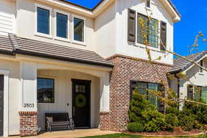 View of front of property featuring brick siding, board and batten siding, and a tile roof