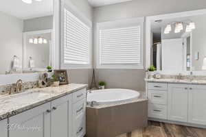 Bathroom featuring a bath, two vanities, a sink, and visible vents