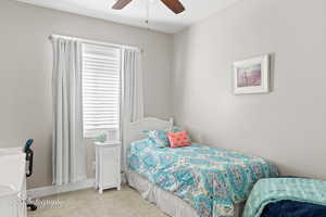 Carpeted bedroom featuring a ceiling fan