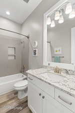 Full bath featuring shower / bathtub combination with curtain, vanity, visible vents, toilet, and wood finished floors