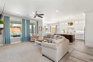 Living room with light wood-type flooring, a ceiling fan, visible vents, recessed lighting, and baseboards