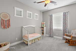 Bedroom with a nursery area, visible vents, baseboards, and carpet