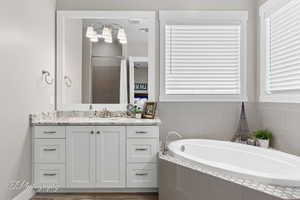 Full bathroom with visible vents, walk in shower, vanity, wood finished floors, and a garden tub