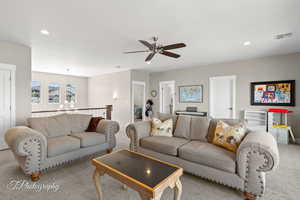 Carpeted living area with recessed lighting, visible vents, ceiling fan with notable chandelier, and baseboards