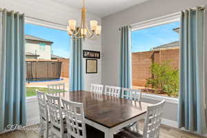 Dining room with a chandelier, wood finished floors, and baseboards