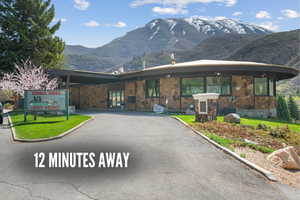 View of front of home with a mountain view, stone siding, and aphalt driveway