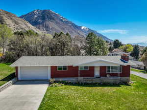 Ranch-style home with concrete driveway, brick siding, a front lawn, and an attached garage