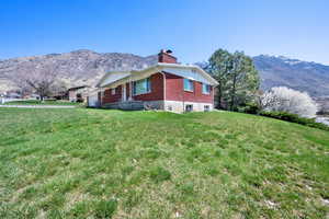 View of property exterior with a lawn, a mountain view, a chimney, and an attached garage
