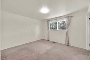 Carpeted empty room featuring visible vents and baseboards