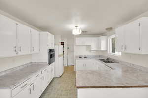 Kitchen featuring white appliances, light floors, washer / clothes dryer, white cabinetry, and a sink