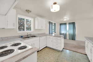 Kitchen with a wealth of natural light, white appliances, a sink, and a peninsula