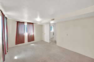 Spare room with a textured ceiling, carpet flooring, and visible vents