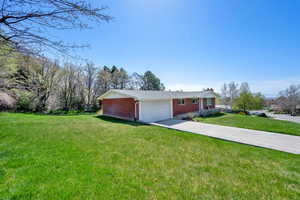 Exterior space with a front yard, driveway, brick siding, and a garage