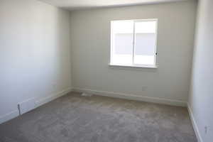 Carpeted spare room featuring visible vents and baseboards