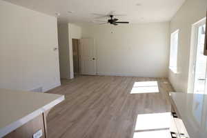 Unfurnished living room featuring light wood finished floors, baseboards, a ceiling fan, and visible vents