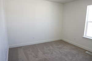 Spare room featuring visible vents, baseboards, and carpet floors