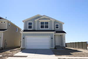 Traditional-style home with board and batten siding, driveway, a garage, and fence