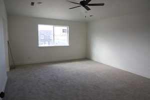 Carpeted spare room with baseboards and ceiling fan