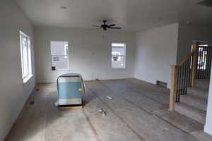 Unfurnished living room with stairs, baseboards, and ceiling fan