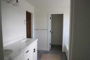 Bathroom with concrete floors, double vanity, a sink, and a walk in closet