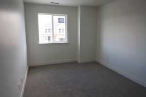 Unfurnished room with carpet floors, baseboards, and visible vents
