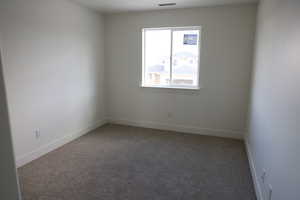 Spare room featuring carpet, visible vents, and baseboards