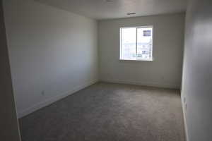 Carpeted empty room with baseboards and visible vents