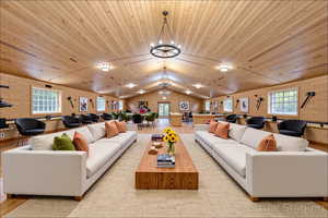 Living room with vaulted ceiling, a chandelier, wooden ceiling, and wood finished floors