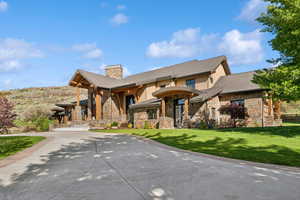 View of front facade featuring stone siding, a chimney, and a front yard