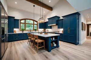 Kitchen with blue cabinets, light countertops, stainless steel built in refrigerator, light wood-style flooring, and recessed lighting