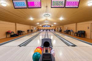 Recreation room featuring bowling, vaulted ceiling, and wooden walls