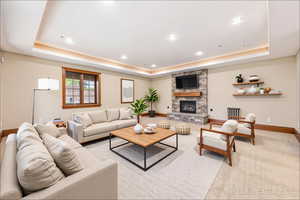 Living room featuring a raised ceiling, a fireplace, and recessed lighting