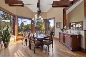 Dining area featuring high vaulted ceiling, a chandelier, and light wood-style floors