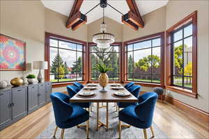 Dining space with a chandelier, light wood-style flooring, beam ceiling, and high vaulted ceiling