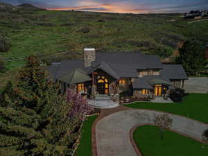 View of front of home featuring stone siding, a chimney, and curved driveway