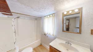 Full bathroom with baseboards, a textured wall, a textured ceiling, vanity, and wood finished floors