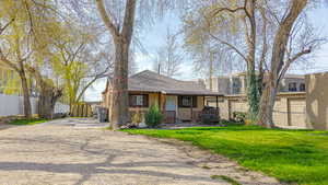 View of front of house with a shingled roof, driveway, fence, and a front lawn