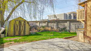 View of patio / terrace featuring an outbuilding, a shed, fence, and central AC