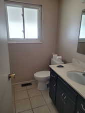 Half bath with vanity, baseboards, tile patterned floors, toilet, and visible vents