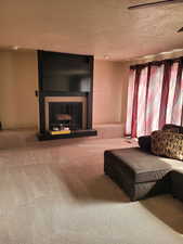 Living room featuring a fireplace, carpet, and a textured ceiling