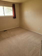 Carpeted spare room with baseboards and visible vents