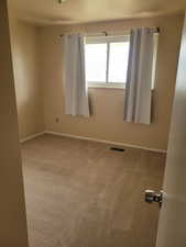 Carpeted spare room with visible vents and baseboards