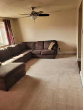 Carpeted living area with ceiling fan