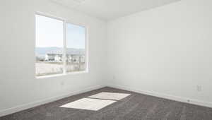 Carpeted empty room with a healthy amount of sunlight, a mountain view, and baseboards