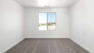 Unfurnished room featuring visible vents, baseboards, and dark colored carpet