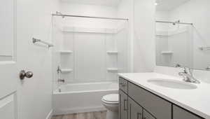 Full bathroom featuring tub / shower combination, vanity, toilet, and wood finished floors