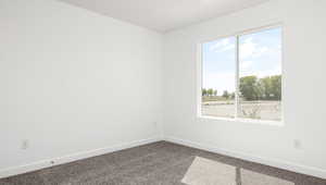 Spare room with baseboards, dark carpet, and a healthy amount of sunlight